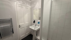 Un baño con lavabo blanco, espejo y ducha.
