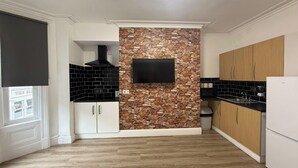 Una cocina moderna con salpicadero de piedra, armarios blancos y negros, y un televisor empotrado.