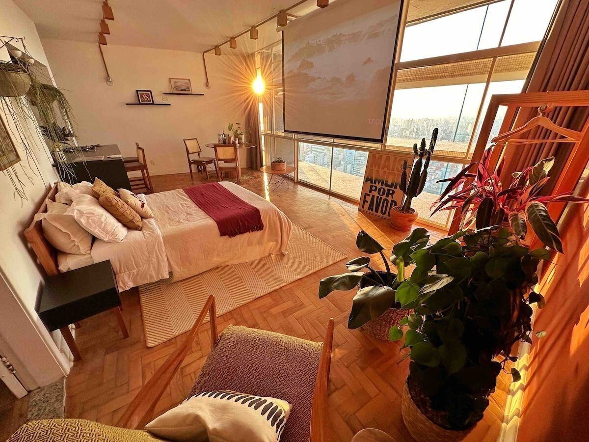 Ein modernes Schlafzimmer mit Bett, Schreibtisch und großem Fenster.