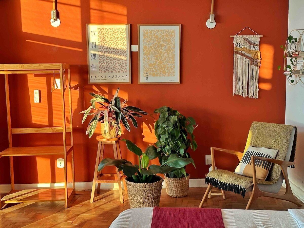 Een kamer met een houten vloer, een houten stoel, een klein tafeltje en twee planten in potten.