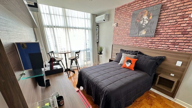 A bedroom with a bed, a desk, a chair, and a window. - 2303B (São Paulo)
