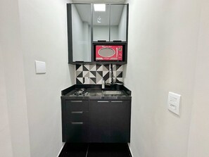 Una kitchenette compacta con microondas, pileta y placares.