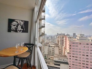 Un balcón con vistas a la ciudad, una mesa con dos sillas y un cuadro en la pared.
