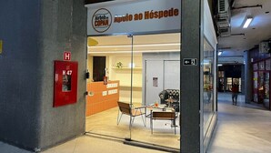 A hotel entrance with a reception desk, a fire alarm, and a glass door leading inside. - 2303B (São Paulo)