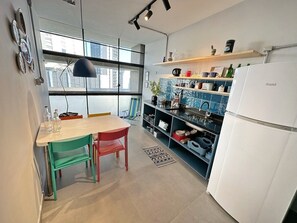 A modern kitchen with a dining area, large windows, and a white refrigerator. - 0054E (São Paulo)