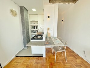 Eine kompakte Küche mit Essbereich, weißen Schränken, einer Mikrowelle und einem Backofen.
