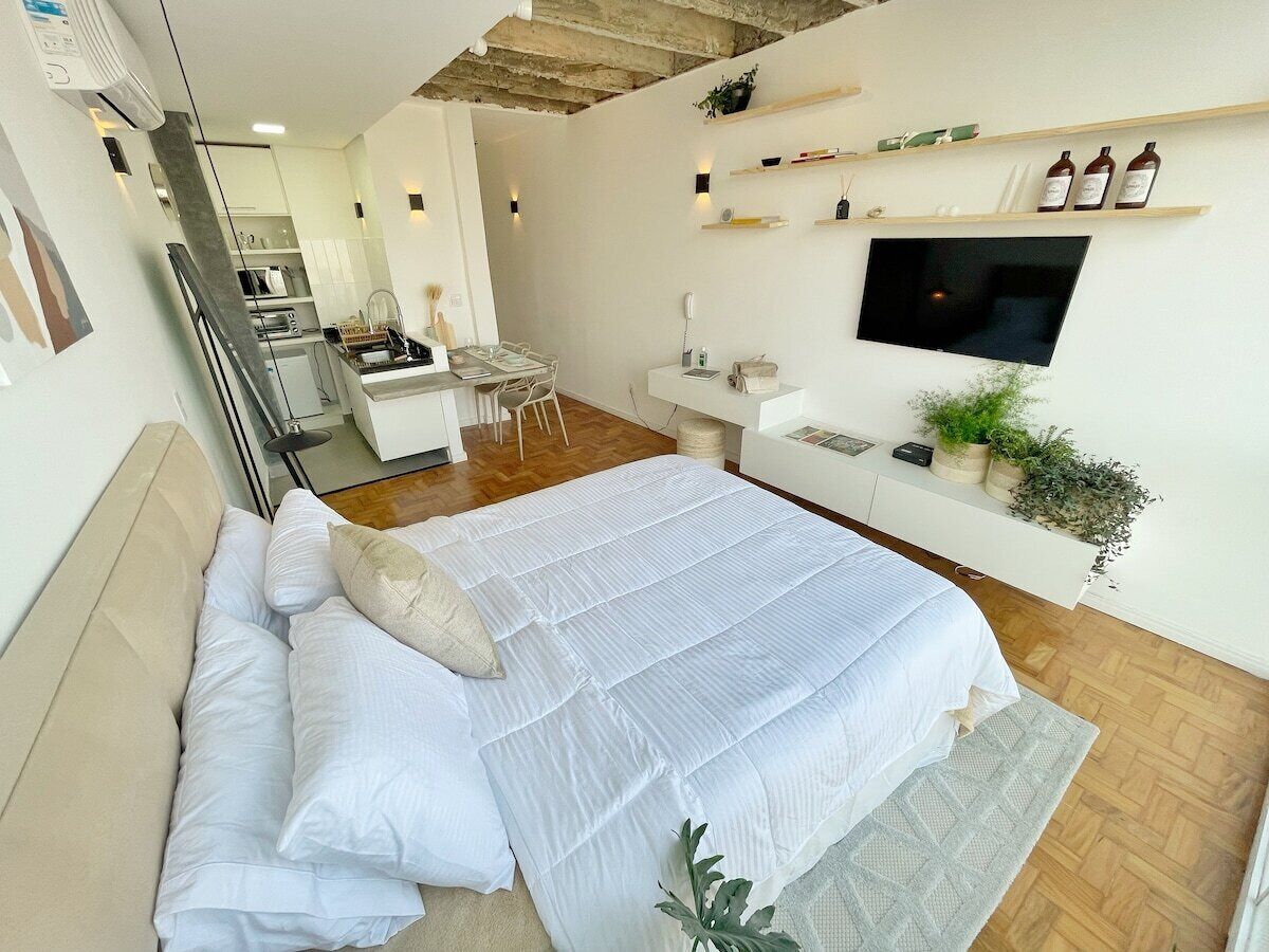 Ein modernes Schlafzimmer mit einem großen Bett, einem Schreibtisch und einem an der Wand befestigten Fernseher.