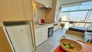 A modern kitchen with a built-in refrigerator, a sink, and a stove. There is a basket with limes on the counter. - 2210B (São Paulo)