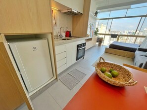 Eine moderne Küche mit einem Einbaukühlschrank, einer Spüle und einem Herd. Auf der Arbeitsplatte steht ein Korb mit Limetten.