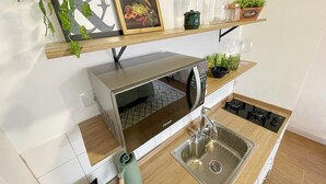 A compact kitchen with a built-in microwave, a stainless steel sink, and a wooden countertop. - 2709B (São Paulo)