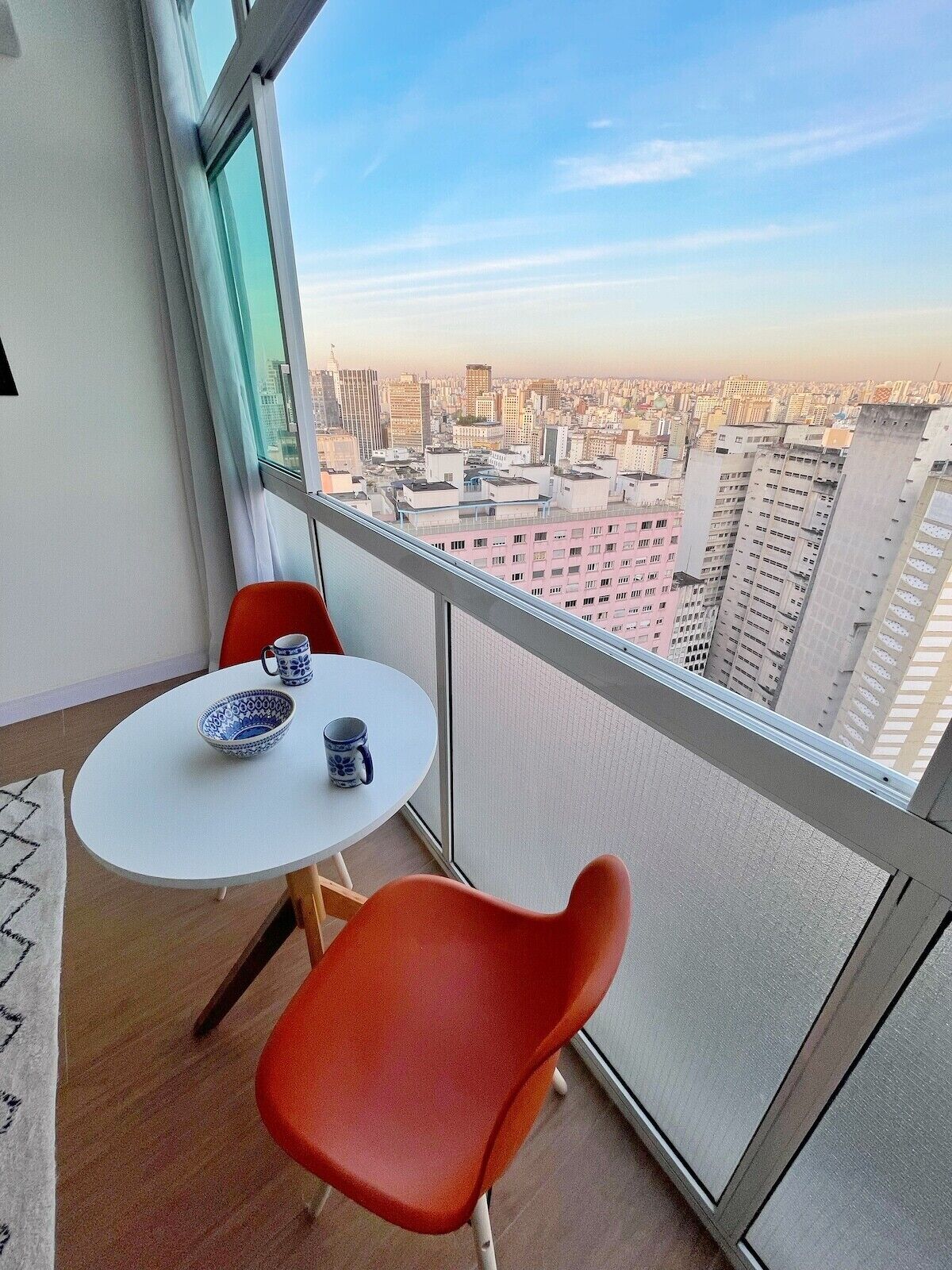 Un piccolo balcone con tavolo e sedie, affacciato su un panorama urbano.