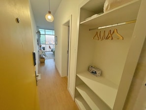 A hallway with a white door, a hanging light fixture, and a closet with a clothing rack. - 2709B (São Paulo)