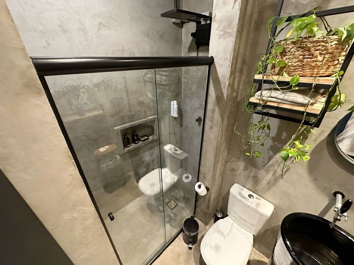 Een moderne badkamer met een douchecabine van glas, een toilet en een wastafel.