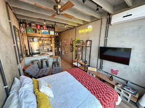 Ein modernes Schlafzimmer mit Bett, Sitzecke und Fernseher.