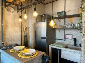 Eine Küche mit Edelstahlkühlschrank, Spüle und einer Arbeitsplatte mit Tellern und Wasserkocher.