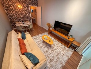 Un salon comprenant un canapé, une table basse, un téléviseur et un coin repas avec des chaises et une table.