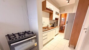 A kitchen with a gas stove, white cabinets, and a stainless steel sink. - Spacious Apt 100m² · 2 Bedrooms in the Iconic Edifício Copan (São Paulo)