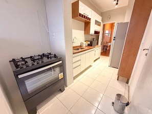 A kitchen with a gas stove, white cabinets, and a stainless steel sink. - Spacious Apt 100m² · 2 Bedrooms in the Iconic Edifício Copan (São Paulo)