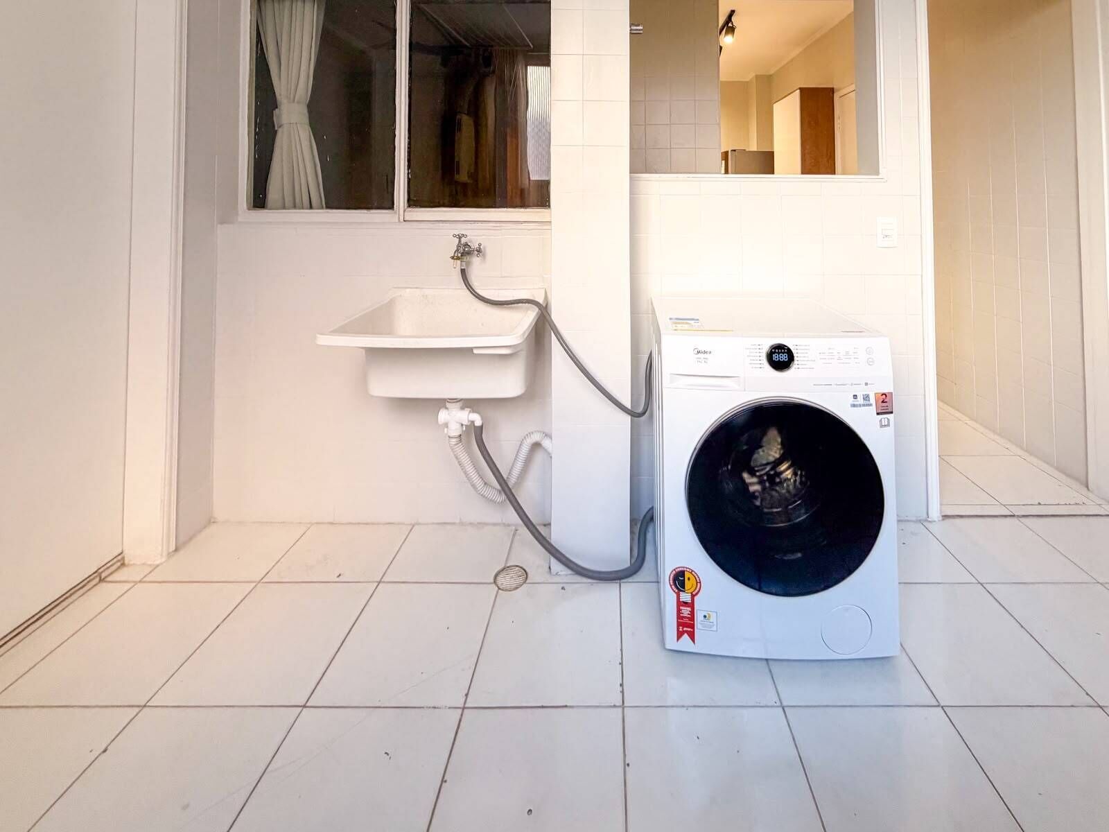 A compact laundry area with a washing machine, a sink, and a window.