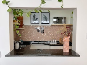 Eine Küche mit einer Granitabdeckung, hängenden Messern, einer Mikrowelle und einer Vase mit Blumen.