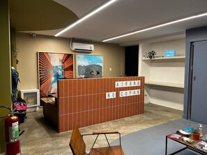 A reception area with a brown partition displaying 'AIRBNB NO COPAN' and a blue sign above it. - 0211F (São Paulo)