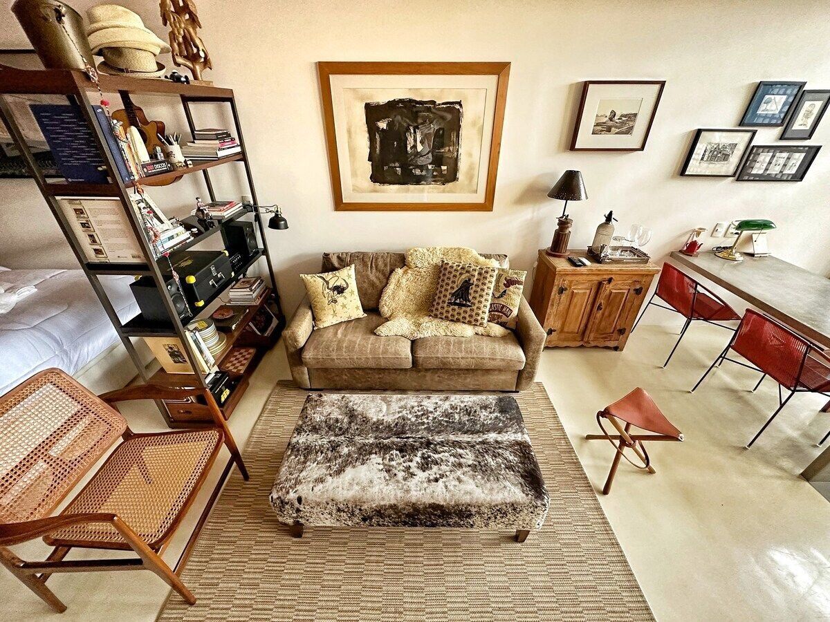 A living room with a sofa, ottoman, and a bookshelf.