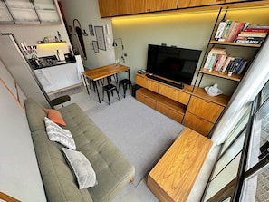 A compact living space with a sofa, a dining area, a TV, and a bookshelf. - 1305B (São Paulo)