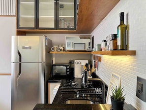 A compact kitchen with a stainless steel refrigerator, a microwave, a toaster, and a gas stove. - 1305B (São Paulo)