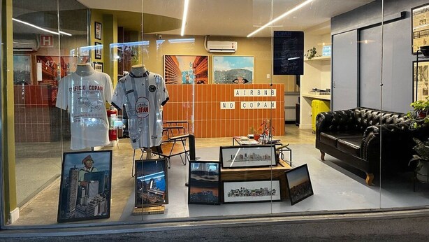 Een hotel lobby met een receptiebalie, ingelijste foto's aan de muur en een zwarte leren bank.