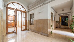 A spacious hallway with a wooden door, a potted plant, and a staircase leading to another room. - Crescenzio 74 Boutique Guest House by Ghor (Rome)