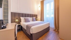 A hotel room with a bed, bedside table, lamp, and a view of the outdoors. - Crescenzio 74 Boutique Guest House by Ghor (Rome)