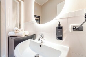 A bathroom with a white sink, a mirror, a towel rack, and a hand soap dispenser. - Crescenzio 74 Boutique Guest House by Ghor (Rome)