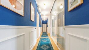 A hallway with blue walls, white wainscoting, a blue carpet, and framed artwork. - Crescenzio 74 Boutique Guest House by Ghor (Rome)