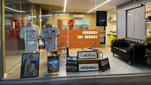 Een hotellobby met een receptiebalie, ingelijste foto's aan de muur en een zwarte leren bank.