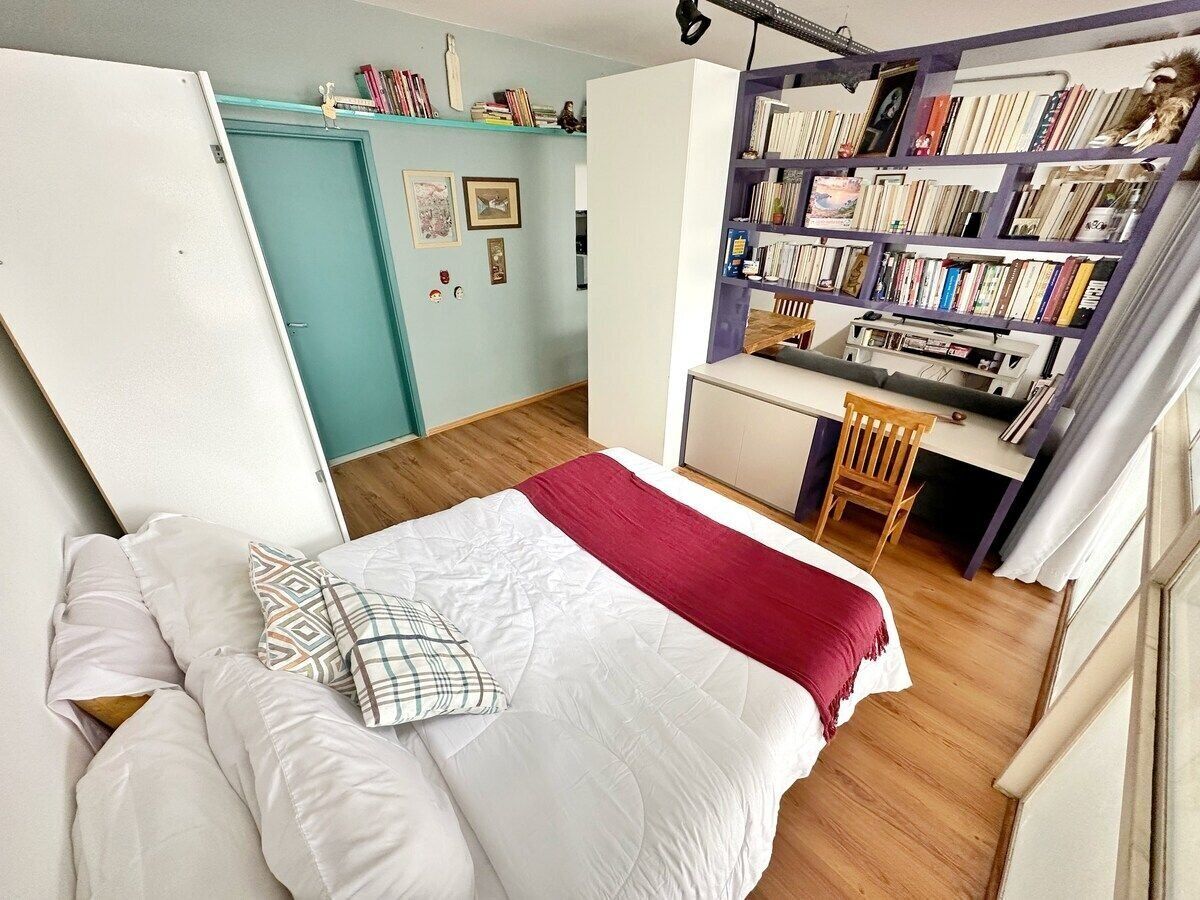 A bedroom with a bed, a desk, and a bookshelf.