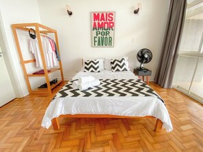 A bedroom with a bed, a wooden ladder with clothes, a wall clock, and a window with curtains. - 2919B (São Paulo)