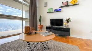 A modern living room with a round table, a flat-screen TV, and a city view. - 2919B (São Paulo)
