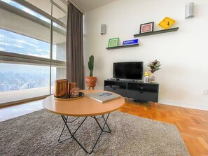 A modern living room with a round table, a flat-screen TV, and a city view. - 2919B (São Paulo)