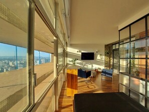 Ein modernes Interieur mit einem großen Fenster, einem Flachbildfernseher und einem Holztisch.