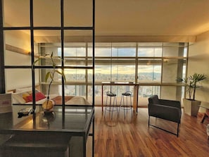 A modern living room with a city view, a dining area with stools, and a large window. - 2716B (São Paulo)