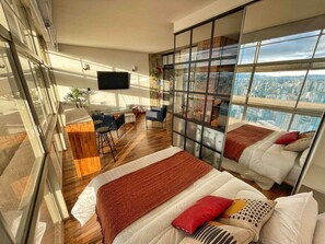 Ein modernes Schlafzimmer mit Blick auf die Stadt, einem Schreibtisch und einem Stuhl.