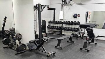 Une salle de sport équipée de matériel de musculation, de bancs et d’haltères.