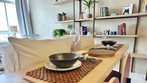 A dining table with a bowl, chopsticks, and a placemat. There is a bookshelf in the background with books and decorative items. - 3206B (São Paulo)
