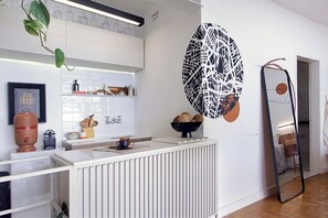A modern kitchen with white cabinetry, a white countertop, and a large decorative wall piece. - 3217B (São Paulo)