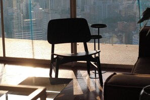 A modern interior with a view of a cityscape through large windows, a black chair, and a small round table. - 3217B (São Paulo)