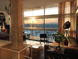 A modern living room with a large window, a sofa, a coffee table, and a potted plant. - 3217B (São Paulo)