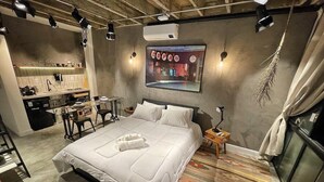 A hotel room with a large bed, a desk with a chair, a small table, and a wall-mounted TV. - 2006B (São Paulo)