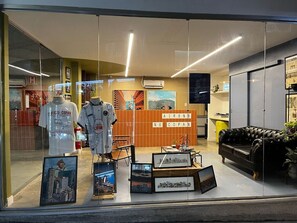A hotel lobby with a reception desk, framed pictures on the wall, and a black leather sofa. - 2006B (São Paulo)