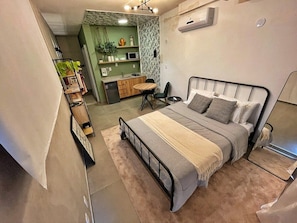 A compact bedroom with a bed, bedside table, and a small seating area. - 1902B (São Paulo)
