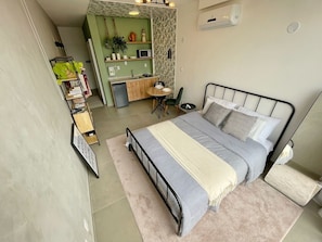 A compact bedroom with a bed, bedside table, and a small desk area. - 1902B (São Paulo)